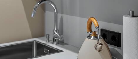 Una cocina con un grifo moderno, un hervidor y un dispensador de toallas de papel.