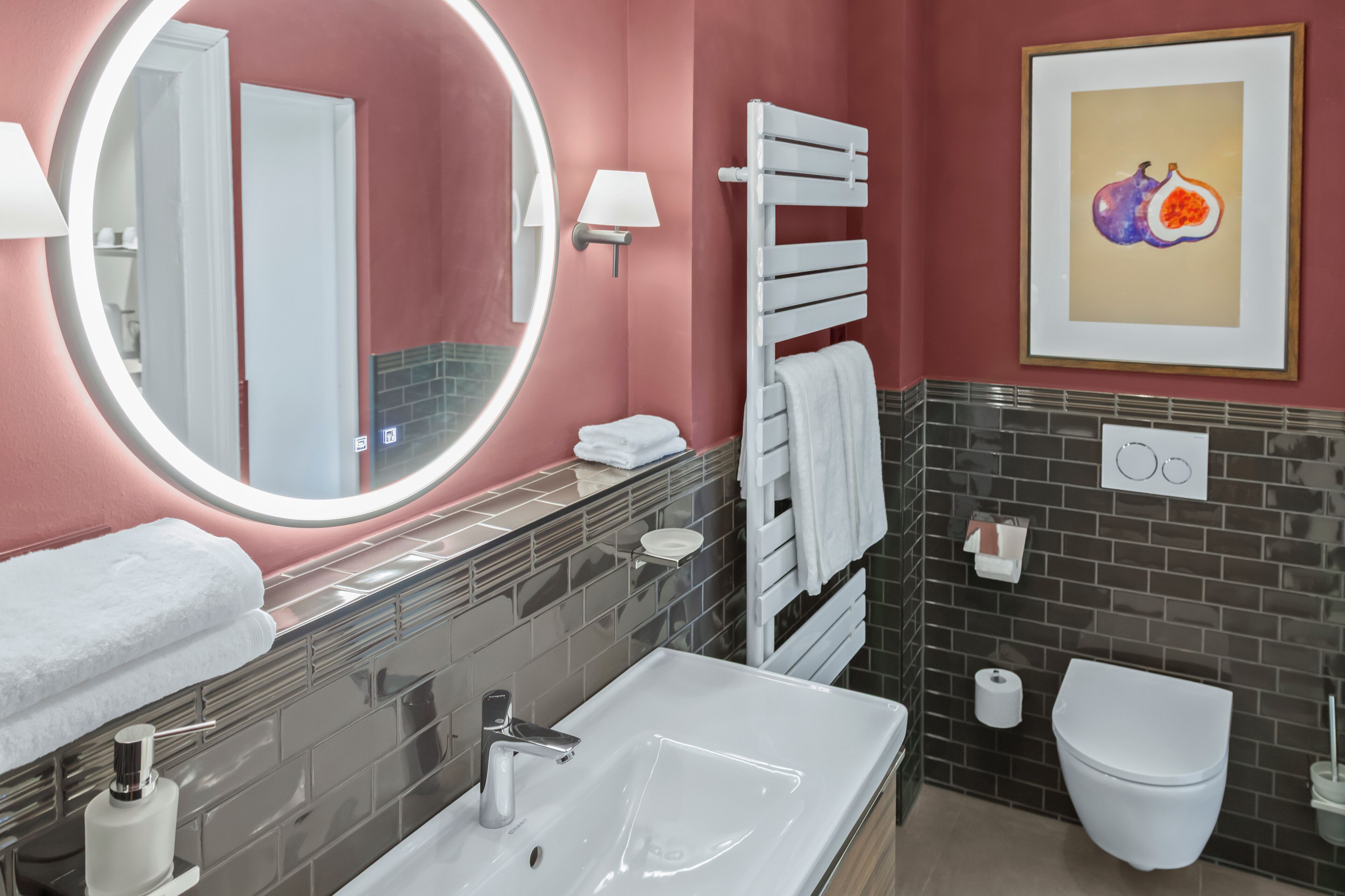 A modern bathroom with a round mirror, white sink, and a toilet.