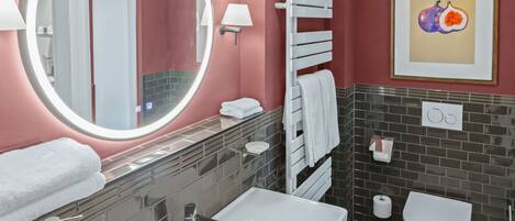 A modern bathroom with a round mirror, white sink, and a toilet.