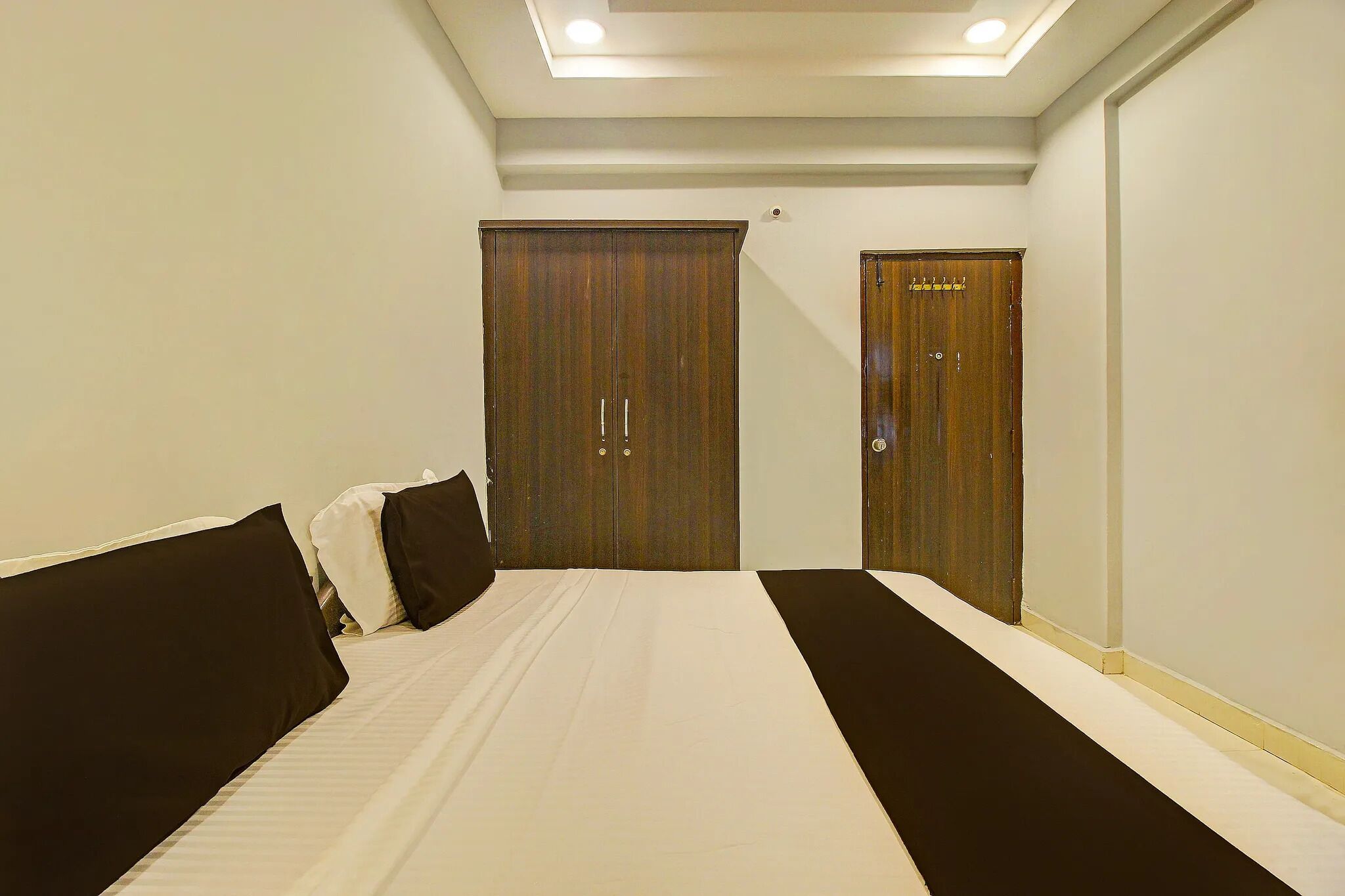 A hotel room with a large bed, two wardrobes, and a ceiling light.