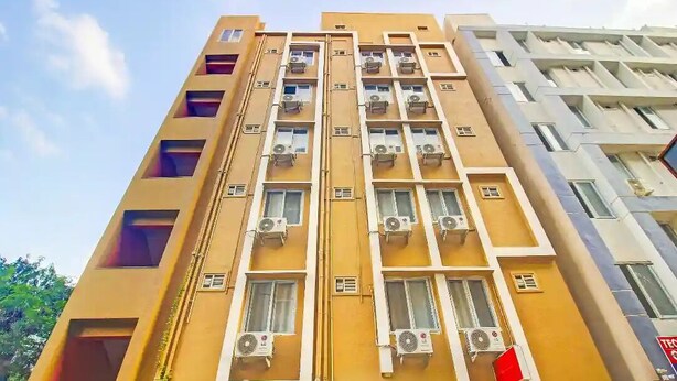 A multi-story building with air conditioning units on each floor, a visible window, and a flag.