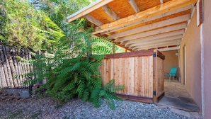 A covered outdoor area with a wooden deck, a wooden fence, and a gravel ground.