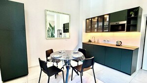 A compact kitchen with a dining area, featuring a round table with chairs, a mirror, and built-in cabinets. - Experience Authentic Italian Elegance Between Rome and the Sea (Civitavecchia)