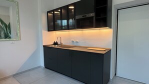 A modern kitchen with dark cabinetry, a stainless steel sink, and under-cabinet lighting. - Experience Authentic Italian Elegance Between Rome and the Sea (Civitavecchia)