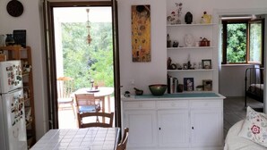 Een keuken met een eettafel, een hanglamp en uitzicht op groen.