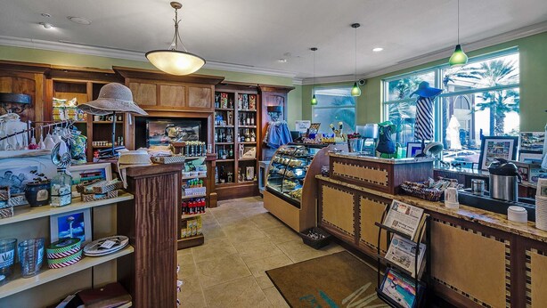 A cozy cafe with wooden decor, a bakery display, and a view of palm trees outside. - Portofino Island Resort 1-1708 (Pensacola Beach)
