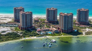 A high-rise hotel with multiple floors, a beach view, and a marina with boats. - Portofino Island Resort 1-1708 (Pensacola Beach)