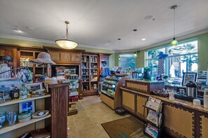 A bakery with a display case, shelves with baked goods, and a counter with a cash register. - Portofino Island Resort 1-1708 (Pensacola Beach)