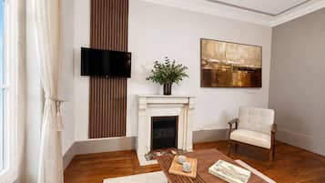 A modern living room with a fireplace, a television, a painting, and a comfortable armchair.