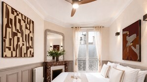A hotel room with a large bed, a fireplace, a mirror, and artwork on the walls. - 1609 CroixNivert (Paris)