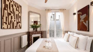 Una habitación de hotel con una cama grande, una chimenea, un espejo y obras de arte en las paredes.