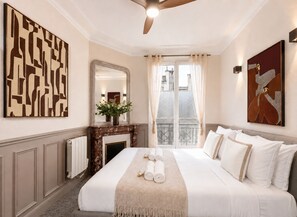 A hotel room with a large bed, a fireplace, a mirror, and artwork on the walls. - 1609 CroixNivert (Paris)