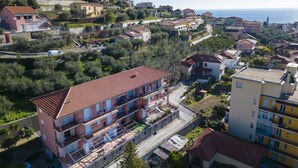 An aerial view of a residential area with multi-story buildings, balconies, and a clear view of the sea.