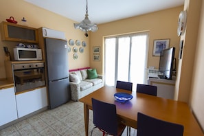 Une cuisine compacte équipée d’un réfrigérateur, d’un four à micro-ondes, d’un four et d’une table à manger avec des chaises.