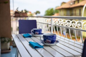 Un balcone con due tazze blu su un tavolo bianco, un tovagliolo blu e una ringhiera bianca.