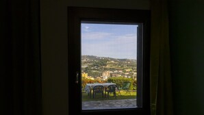 A window with a view of a hillside town, a table with chairs, and a door frame.