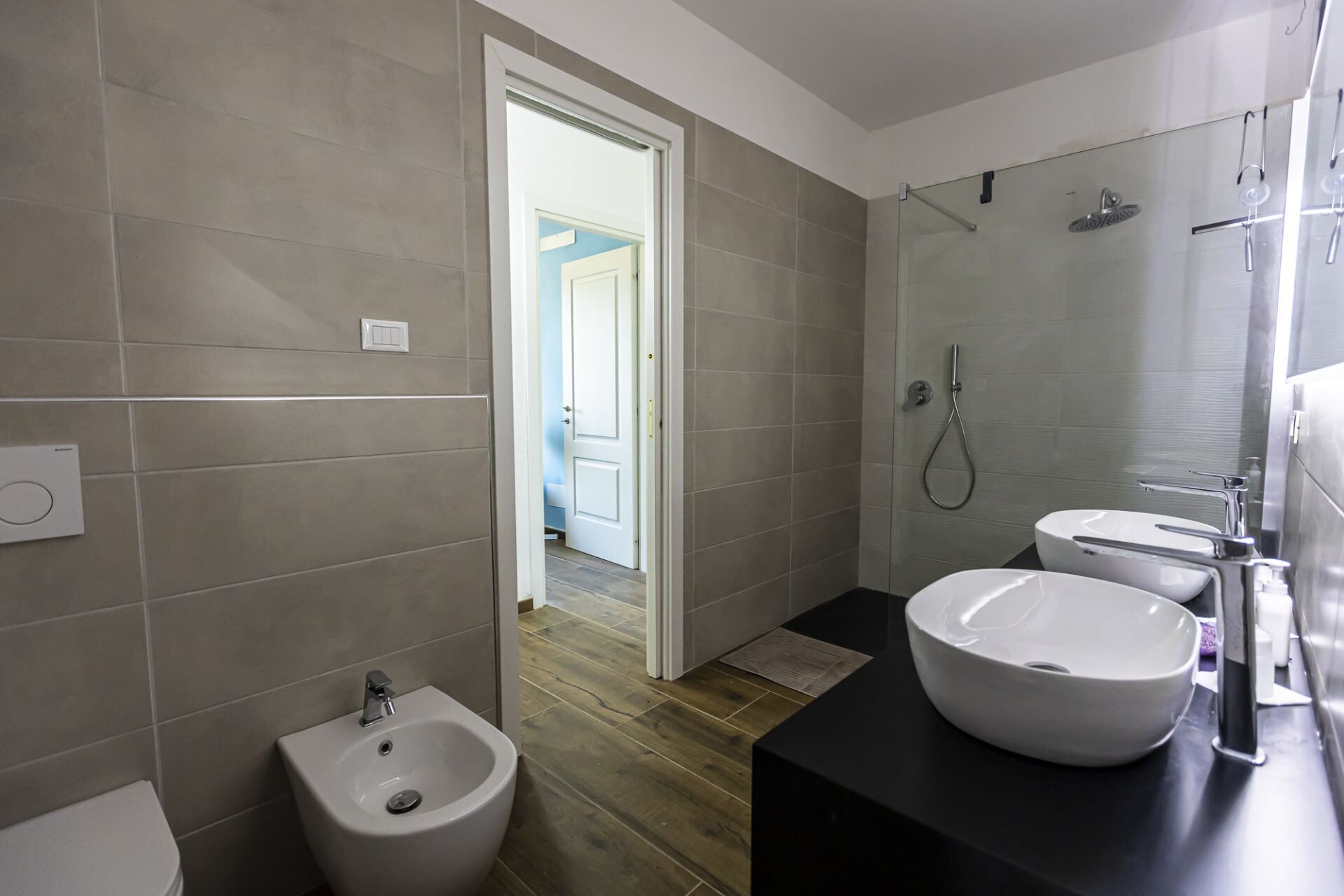 A modern bathroom with a bidet, a sink, and a shower.