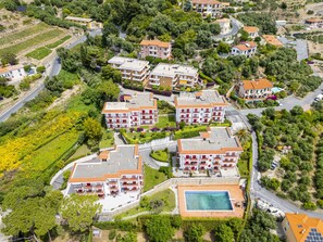 Luchtbeeld van een woongebied met meerdere appartementencomplexen, een zwembad en veel groen eromheen.