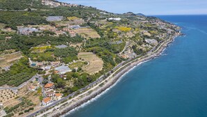 An aerial view of a coastal town with a mix of residential buildings, green spaces, and a rocky shoreline.