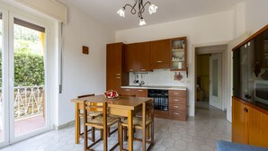 A modern kitchen with wooden cabinets, a dining table with chairs, and a built-in oven.