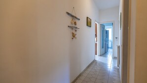 A hallway with a tiled floor, a wooden door frame, and a wall-mounted decoration.