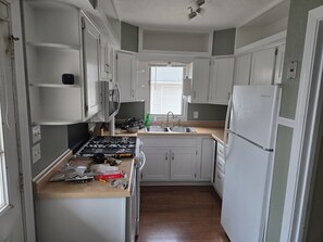 A compact kitchen with white cabinets, a stove, a sink, and a refrigerator. - Fully updated 3-bedroom home near college and hospitals. (Sioux City)