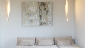 A minimalist living room with a neutral color scheme, featuring a sofa and abstract art on the wall. - Rental in Rome Mellini View Apartment (Rome)