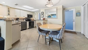 A modern kitchen with a dining area, featuring a central island, built-in appliances, and a large mirror above the sink.