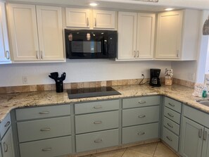 A kitchen with white cabinets, a black microwave, and a coffee maker.