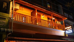 A two-story building with a balcony and a sign that reads "Le Apex."