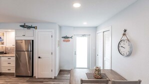 Eine moderne Küche mit einem Edelstahlkühlschrank, weißen Schränken und einem Essbereich mit Holztisch und -stühlen.