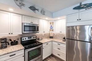 Una cocina moderna con armarios blancos, electrodomésticos de acero inoxidable y salpicadero.