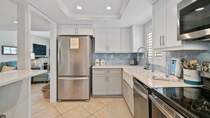 Una cocina moderna con armarios blancos, electrodomésticos de acero inoxidable y un salpicadero de azulejos.