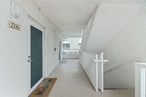 A corridor with a door, a doormat, and a railing.