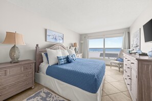 A bedroom with a bed, dresser, and a view of the sea. - Condo 206 - Premium - Your Beachfront Retreat Awaits (Sarasota)