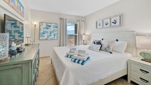 Un dormitorio ordenado con una cama grande, un aparador y una mesita de noche.