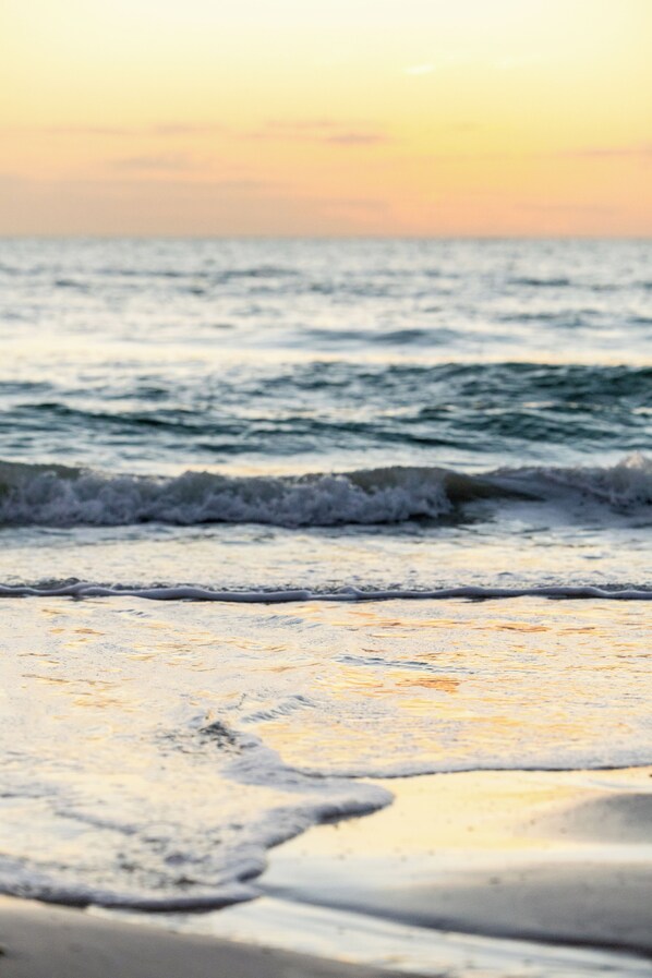 Una playa con olas y un atardecer.