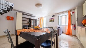 A dining area with a table, chairs, and a kitchen in the background. - Apartment 'Casetta Bella' with Balcony, Wi-Fi and Air Conditioning (Condrò)