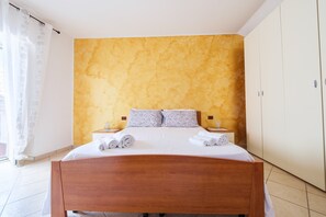 A bedroom with a wooden bed, a yellow textured wall, and a white wardrobe.
