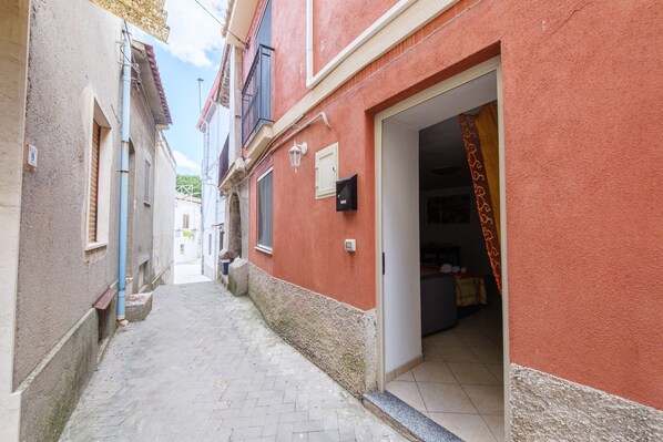 A narrow alleyway with buildings on either side, a visible door, and a tiled floor.
