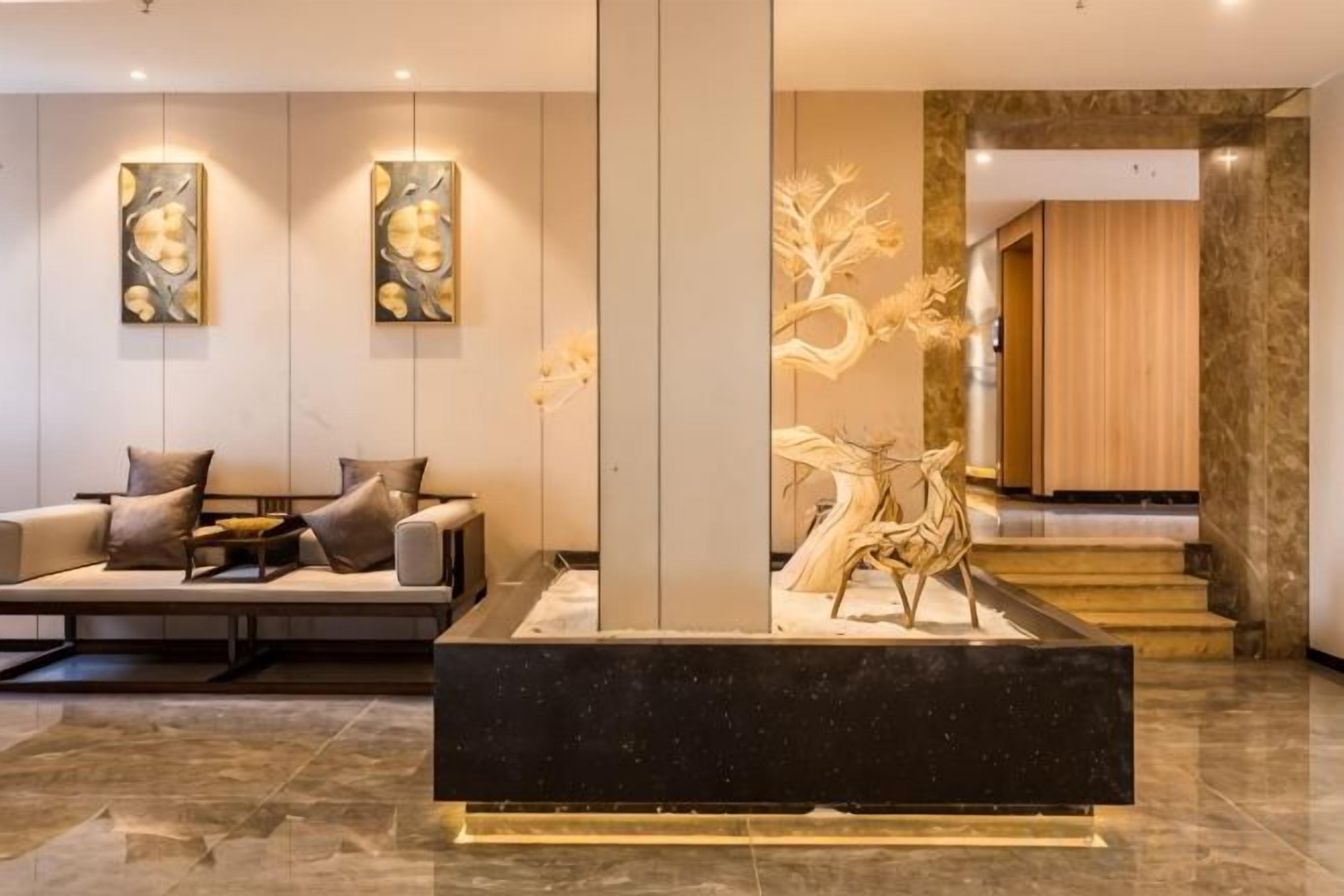 A modern lobby with a reception desk, seating area, and a staircase leading to another level.
