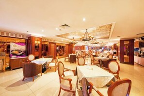 A hotel dining area with multiple tables and chairs, a bar, and a view of the street. - Great Wall Hotel (Chongqing)