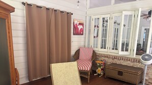 Een gezellige kamer met een rieten stoel, een comfortabele bank en een ventilator.
