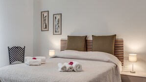 A neatly made bed with rolled towels and pillows, a headboard, wall-mounted picture frames, and bedside lamps. - Hela - Sweet Dreams in Florence (Sesto Fiorentino)