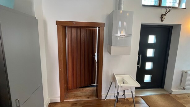A modern kitchen with a wooden door, a white cabinet, and a black door with windows. - Former church in new splendor (Oranienbaum-Wörlitz)