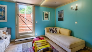 A room with a sofa, a bed, a staircase, and a door leading outside. - Cocteau Guest Room with Shared Terrace, Wi-Fi, and Air Conditioning (Menton)