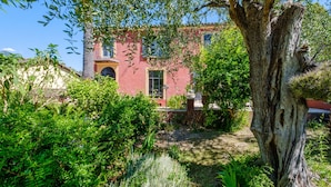 A red building with a large tree in the foreground, surrounded by lush greenery. - Cocteau Guest Room with Shared Terrace, Wi-Fi, and Air Conditioning (Menton)
