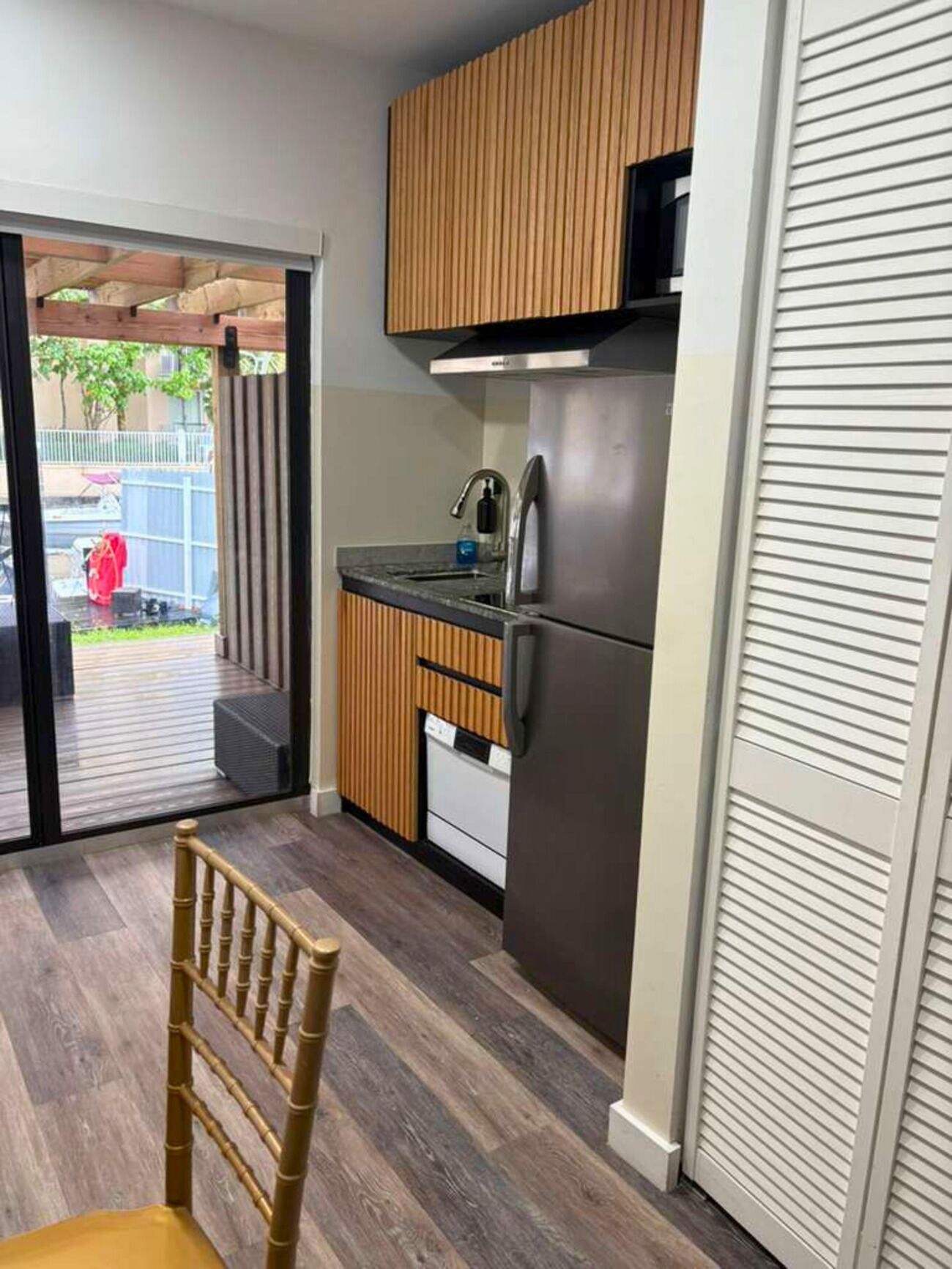 A modern kitchen with wooden cabinets, a stainless steel refrigerator, and a built-in oven.