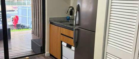 A modern kitchen with wooden cabinets, a stainless steel refrigerator, and a built-in oven.