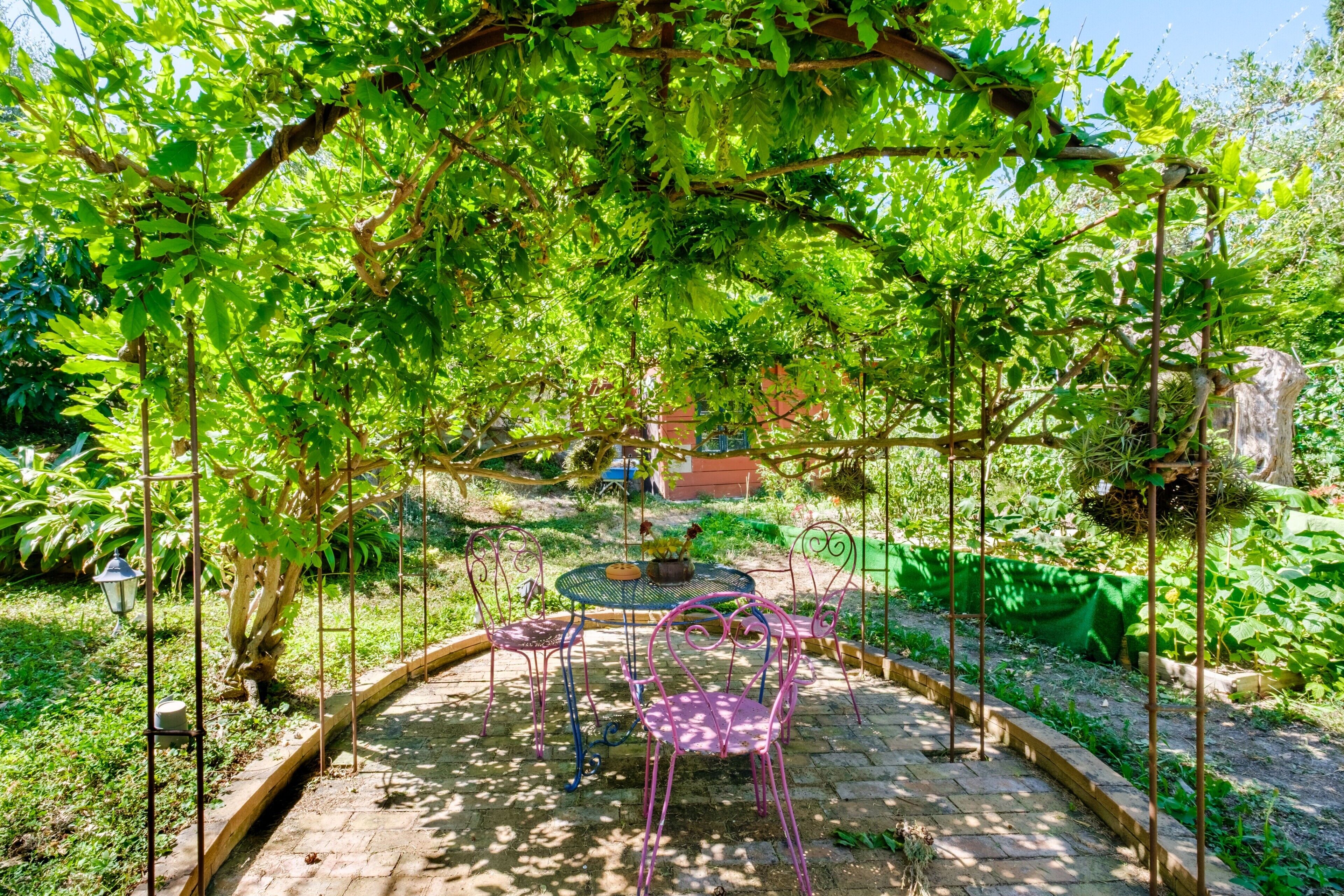 Un giardino con una pergola, un tavolo e delle sedie.